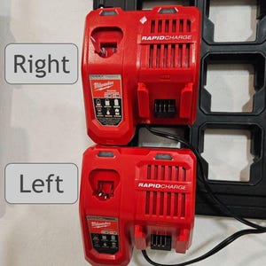 May include: Two red Milwaukee Rapid Charge battery chargers mounted on a black wall mount. The chargers have a black power cord and are labeled "RAPIDCHARGE".
