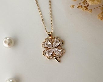 May include: A gold chain necklace with a four-leaf clover pendant adorned with clear cubic zirconia stones.
