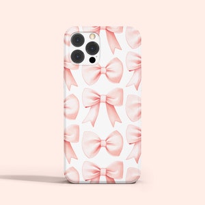 K&ouml;nnte beinhalten: Eine wei&szlig;e Handyh&uuml;lle mit einem Muster aus rosa Schleifen. Die H&uuml;lle hat einen Ausschnitt f&uuml;r die Kamera und einen wei&szlig;en Hintergrund.