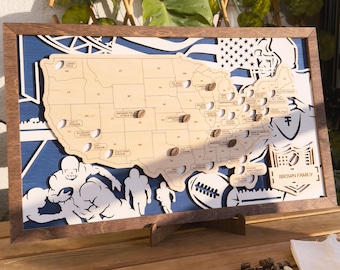May include: A wooden map of the United States with a blue background and white football players. The map is decorated with coffee beans and the text "BROWN FAMILY".