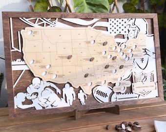 May include: Wooden United States map with football stadium locations and football-shaped markers. The map is framed in dark brown wood, with white cut-out football players and a football. The text "DAVID'S FOOTBALL TOUR" is visible.