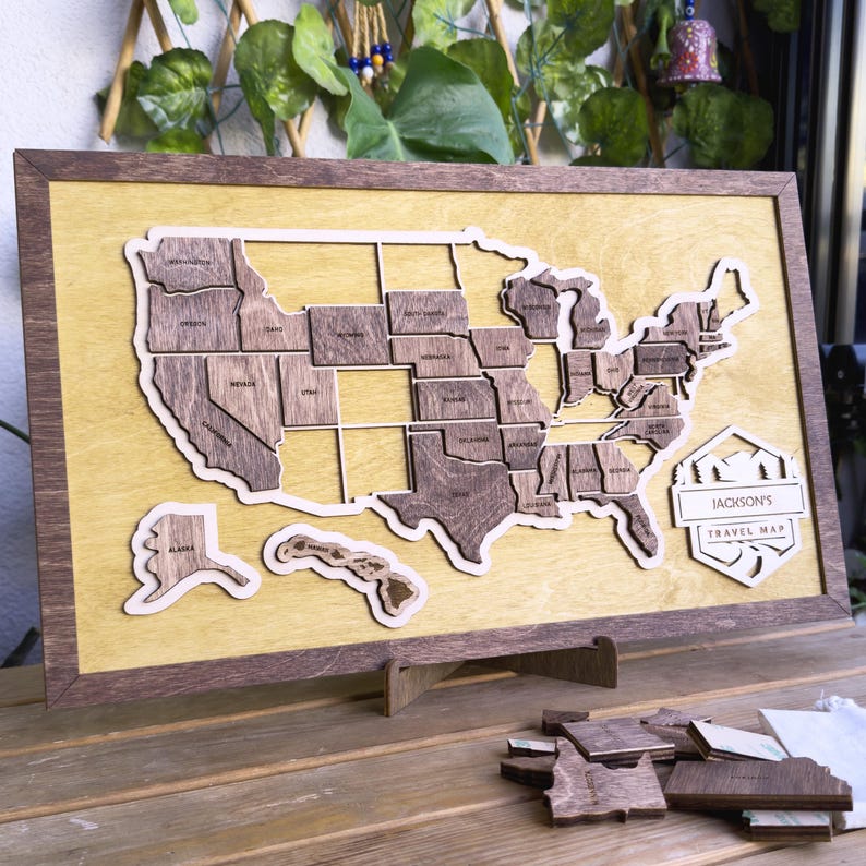 May include: A wooden map of the United States with each state as a separate piece. The map is mounted on a wooden frame and has a stand. The map is labeled "Jackson's Travel Map".