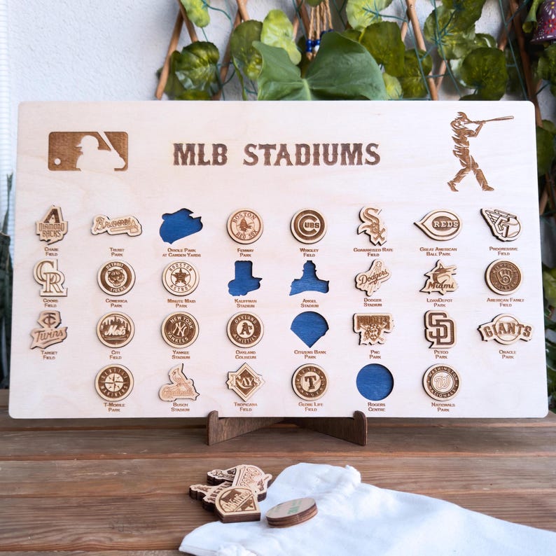 May include: A wooden board with the title "MLB STADIUMS" and a baseball player silhouette. The board features 30 circular wooden cutouts, each representing a different MLB stadium with the team logo and stadium name.