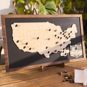 May include: A wooden map of the United States with a black frame and a stand. The map has holes for placing small wooden footballs to mark locations. The map also has the text "Brown Family Football Stadium Map" on the right side.