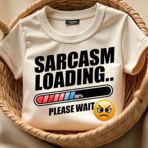 Puede incluir: Una camiseta beige con el texto "Sarcasm Loading..." y una barra de progreso que está llena al 90%. La barra de progreso es roja, azul y blanca. Debajo de la barra de progreso está el texto "Please Wait" y un emoji enojado.