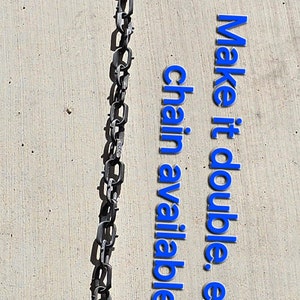 May include: Two black metal chains with sharp points at the ends. The chains are hanging straight down on a light gray concrete surface. The text "Make it a double. Extra chain available." is written in blue letters on the concrete.