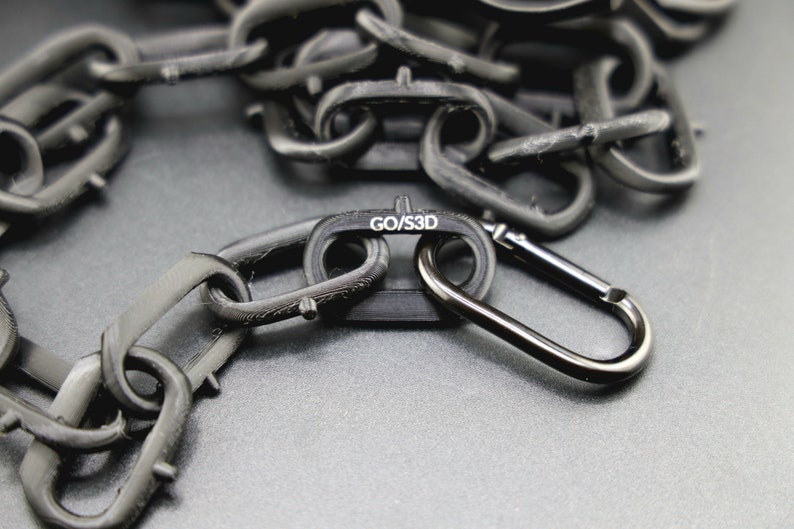 May include: A black chain with a black carabiner clip. The chain has a label that reads "GO/S3D".