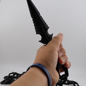 May include: A black plastic dagger with a serrated blade and a chain attached to the handle.