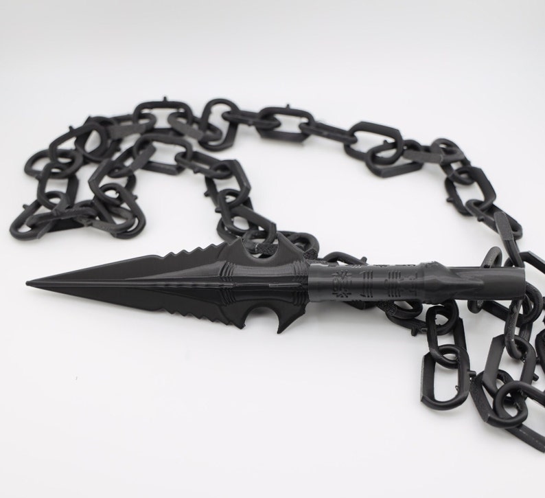 May include: A black chain with a sharp, pointed spear-like tip. The chain is made of metal and has a dark, matte finish.
