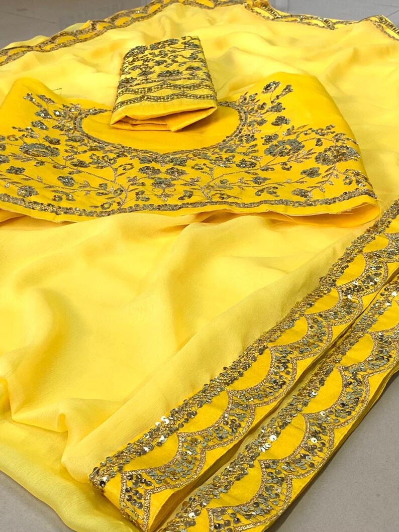 Pu&ograve; includere: Un sari giallo brillante con ricami intricati e dettagli di paillettes. Il sari presenta una blusa abbinata con ricami floreali e un bordo smerlato. Il tessuto appare leggero e fluido, ideale per occasioni speciali.