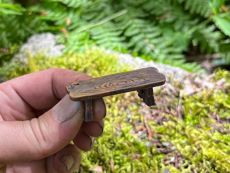 May include: A miniature wooden bench with a rustic brown finish and a wood grain pattern. The bench has four legs and is made of a sturdy material.