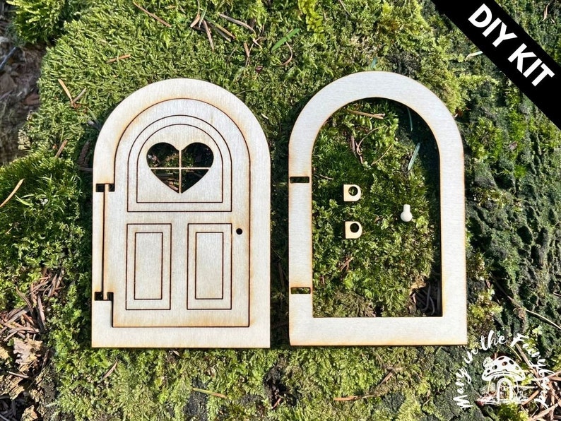 May include: DIY kit for a wooden fairy door with a heart-shaped window and a simple design. The door is unfinished and ready to be painted or stained.