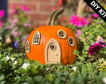 Könnte beinhalten: Ein orangefarbener Kürbis, der als Haus gestaltet ist, mit hellen Holzausschnitten, darunter eine mittige Bogentür und vier Fenster in verschiedenen Formen. Ein schwarzes Eckbanner zeigt den weißen Text DIY KIT oben rechts.