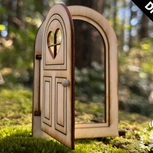 May include: DIY kit for a wooden fairy door with a heart-shaped window and a knob. The door is open and has a light wood finish.