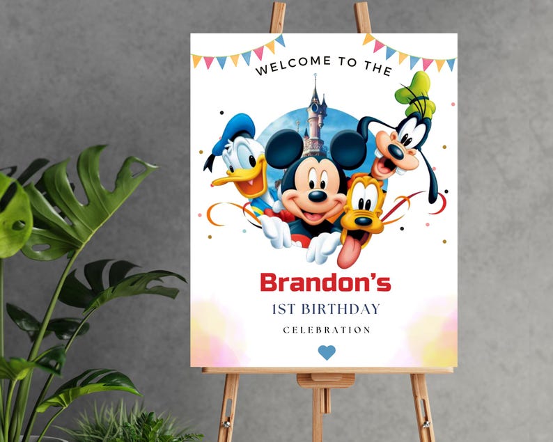 May include: A rectangular birthday sign featuring Mickey Mouse, Donald Duck, Goofy, and Pluto in front of a castle. The text reads WELCOME TO THE, Brandon's, 1ST BIRTHDAY, CELEBRATION, with colorful bunting at the top and a small blue heart at the bottom.