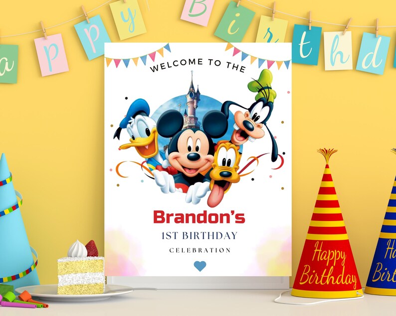 May include: A rectangular birthday sign featuring Mickey Mouse, Donald Duck, Goofy, and Pluto in front of a castle. The text reads WELCOME TO THE, Brandon's, 1ST BIRTHDAY, and CELEBRATION, with colorful bunting at the top and a small blue heart at the bottom.