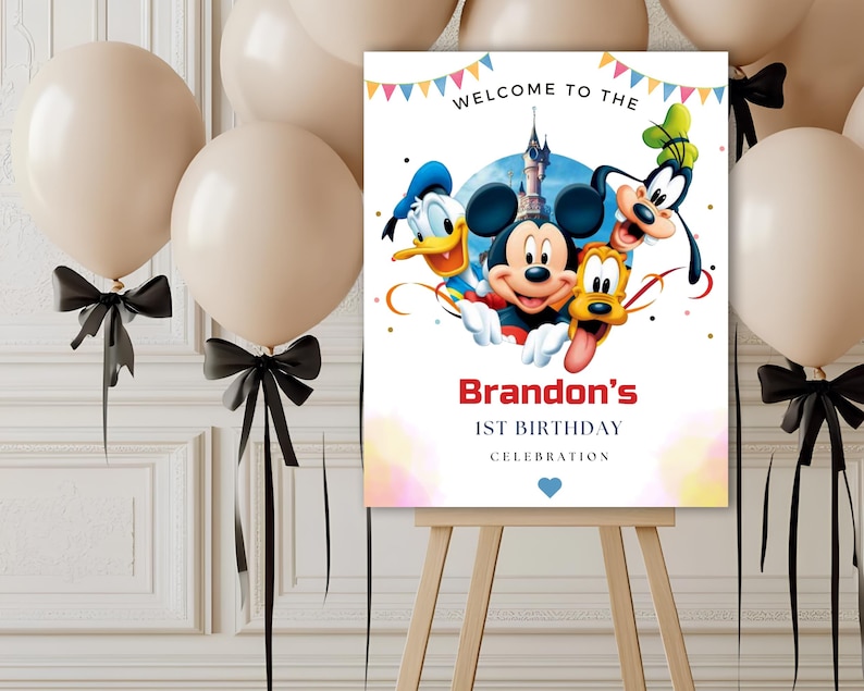 May include: A rectangular birthday sign on a wooden easel featuring Mickey Mouse, Donald Duck, Goofy, and Pluto in front of a castle. The text reads WELCOME TO THE, Brandon's, 1ST BIRTHDAY, CELEBRATION, with colorful bunting and a small blue heart.