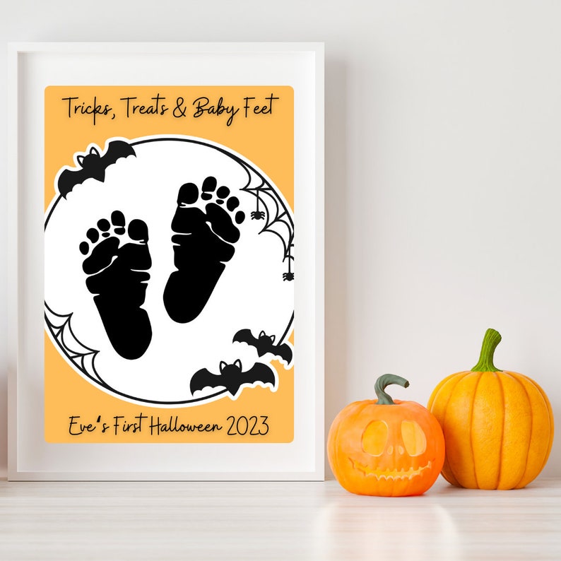 Pode incluir: Uma moldura branca com fundo laranja e texto preto que diz "Tricks, Treats & Baby Feet". H&aacute; duas pegadas de beb&ecirc; pretas dentro de um c&iacute;rculo branco com morcegos pretos e teias de aranha. O texto "Eve's First Halloween 2023" est&aacute; abaixo do c&iacute;rculo.