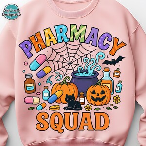 May include: Pink sweatshirt with a colorful "PHARMACY SQUAD" graphic. The design includes pumpkins, pills, a black cat, a spiderweb, and a cauldron. A fun, Halloween-themed design.