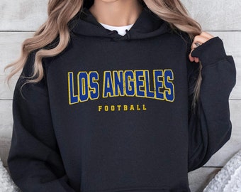 May include: Black hoodie with a yellow and blue "Los Angeles Football" graphic.