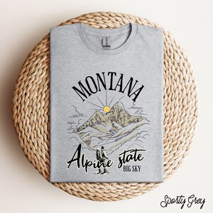 Folded Gildan 64000 Montana hiking tee with nature-inspired graphic, soft cotton fabric