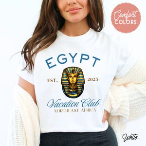 May include: White t-shirt with a blue and gold graphic of a pharaoh's head. The text "EGYPT EST. 2025 Vacation Club NORTHEAST AFRICA" is printed on the shirt.