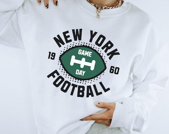 May include: White sweatshirt with a black and green graphic print that says "New York Football" with a football graphic and the numbers 19 and 60. The graphic also says "Game Day" inside the football.