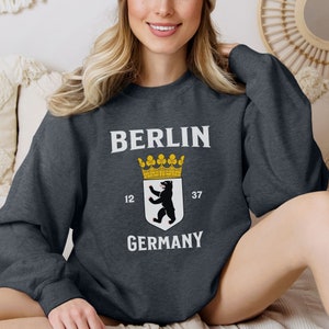 May include: A dark gray sweatshirt with the text "BERLIN GERMANY" and a black bear with a crown on a white shield.