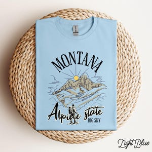 Folded Gildan 64000 Montana hiking tee with nature-inspired graphic, soft cotton fabric