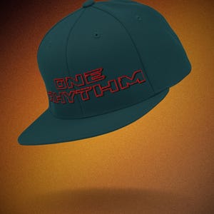 Op de afbeelding: Een tealblauwe baseballpet met een rood geborduurd logo met de tekst "ONE RHYTHM".