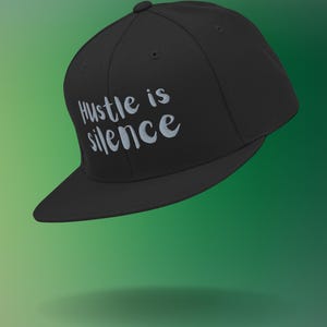 May include: Black baseball cap with a white embroidered phrase "Hustle is silence" on the front.