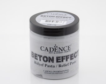 Puede incluir: Un tarro blanco de pasta de relieve Beton Effect de Cadence. El tarro tiene una tapa negra y una etiqueta con el texto "Cadence Art & Hobby Paints Beton Effect Rölyef Pasta / Relief Paste" y "Cadence International London-New York Paris Istanbul Moscow".