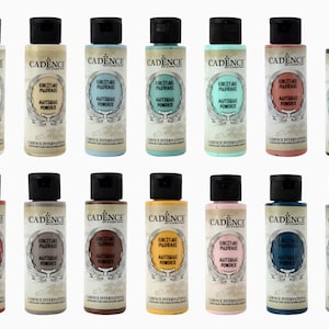 May include: A collection of Cadence Antique Powder bottles in various colors, each with a black cap and label. The labels feature the text "Cadence" and "Antique Powder". The bottles are arranged in rows.