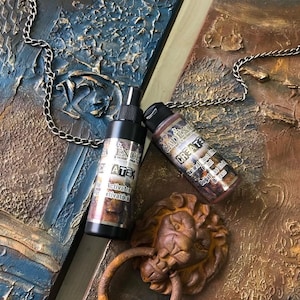 May include: An overhead shot features two textured panels in shades of blue and brown, with a silver chain draped across them. Two bottles of art supplies and a lion-head door knocker are also visible.