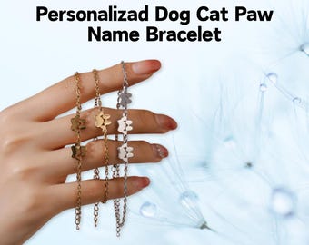 May include: Three gold and silver bracelets with paw print charms. The bracelets are layered on a person's wrist. The background is a blurry image of a dandelion.