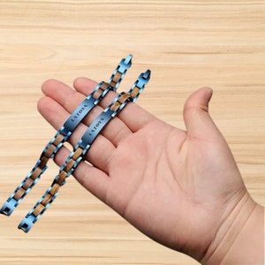 Könnte beinhalten: Zwei blaue und braune Holz-Armbänder mit dem Namen "LAToya" auf den Metallplatten graviert.