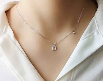 Può includere: Una collana a catena d'argento con un piccolo ciondolo a forma di lettera 'D' tempestato di diamanti e un solo accento di diamante sulla catena.