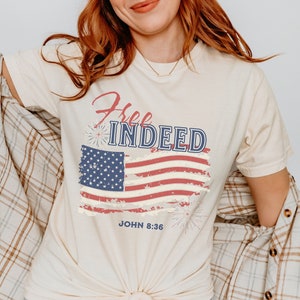 May include: A beige t-shirt with a distressed American flag graphic and the text "Free Indeed" and "John 8:36".