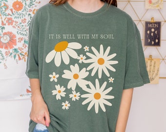 May include: A green t-shirt with a white daisy print and the text "It is well with my soul".