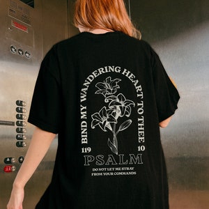 May include: Black t-shirt with a white graphic print of a flower and the text "Bind my wandering heart to thee 119 Psalm 10 Do not let me stray from your commands".