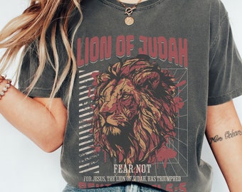 May include: A gray t-shirt with a graphic of a lion's head and the text "Lion of Judah" and "Fear Not" in red. The text below the lion says "For Jesus, the Lion of Judah, has triumphed".