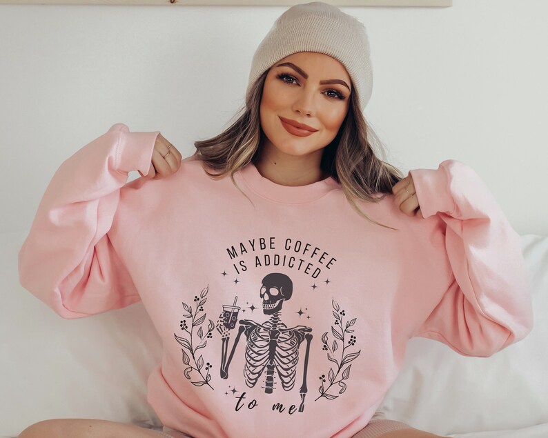 May include: Pink sweatshirt with a skeleton holding a coffee cup and the text "Maybe coffee is addicted to me".