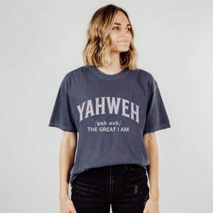 Op de afbeelding: Een donkerblauw T-shirt met witte tekst die "YAHWEH [yah-weh] THE GREAT I AM" zegt.