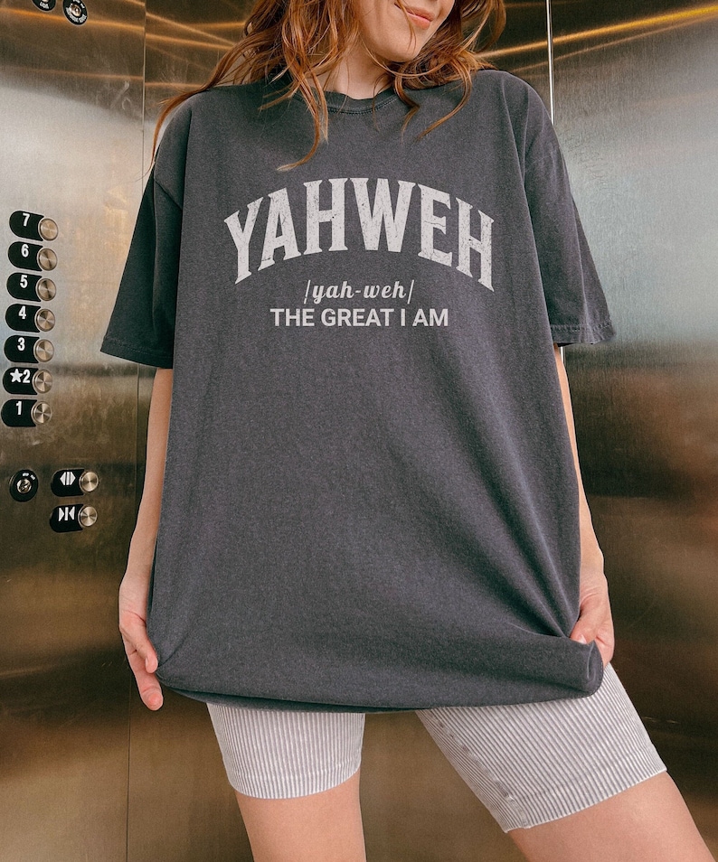 Op de afbeelding: Een zwart T-shirt met witte tekst die "YAHWEH /yah-weh/ THE GREAT I AM" zegt.