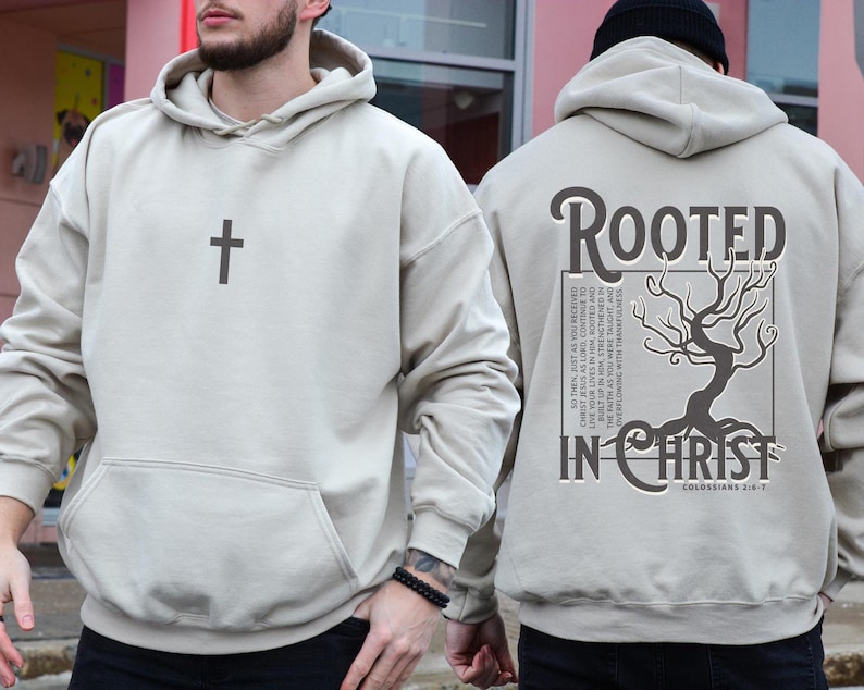 May include: Beige hooded sweatshirt with a cross on the front and the text "ROOTED IN CHRIST" and a tree with roots on the back. The text also includes the scripture reference "Colossians 2:6-7".