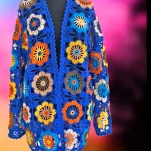 May include: A blue crocheted cardigan with a floral pattern in shades of orange, yellow, brown, and white.