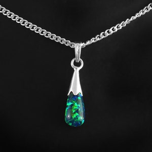 May include: A silver pendant necklace with a teardrop-shaped opal. The opal showcases a vibrant mix of green and blue colours. The pendant hangs from a delicate silver chain, creating an elegant accessory.