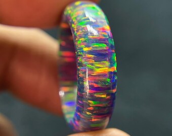 以下が含まれることがあります： 虹色の色が含まれたカラフルなオパールリング。緑、青、紫、オレンジなどがあります。リングは滑らかで磨かれたオパールで作られており、シンプルでエレガントなデザインです。
