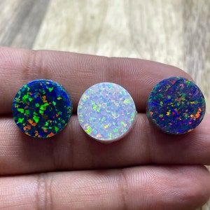 May include: Three round opal cabochons, one blue with green and orange flashes, one white with blue and green flashes, and one black with red and blue flashes.