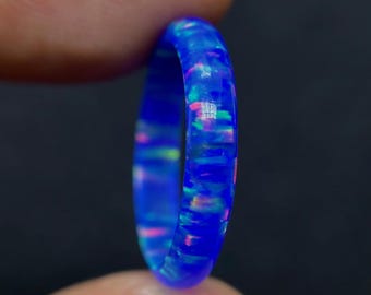 以下が含まれることがあります： 虹色のオパールを埋め込んだ薄い青いリング。リングは樹脂製で、滑らかで磨かれた仕上げになっています。